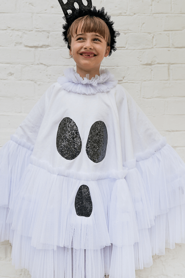 Dziewczynka w stroju duszka z opaską z napisem Boo.