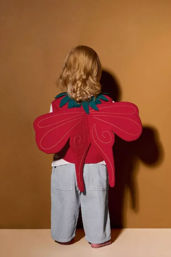 Dziewczynka stoi odwrócona tyłem i ma na plecach truskawkowy motyw.