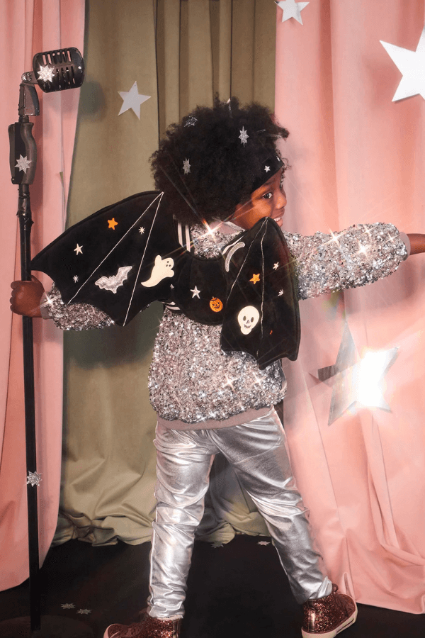 Dziecko w stroju nietoperza stoi tyłem.