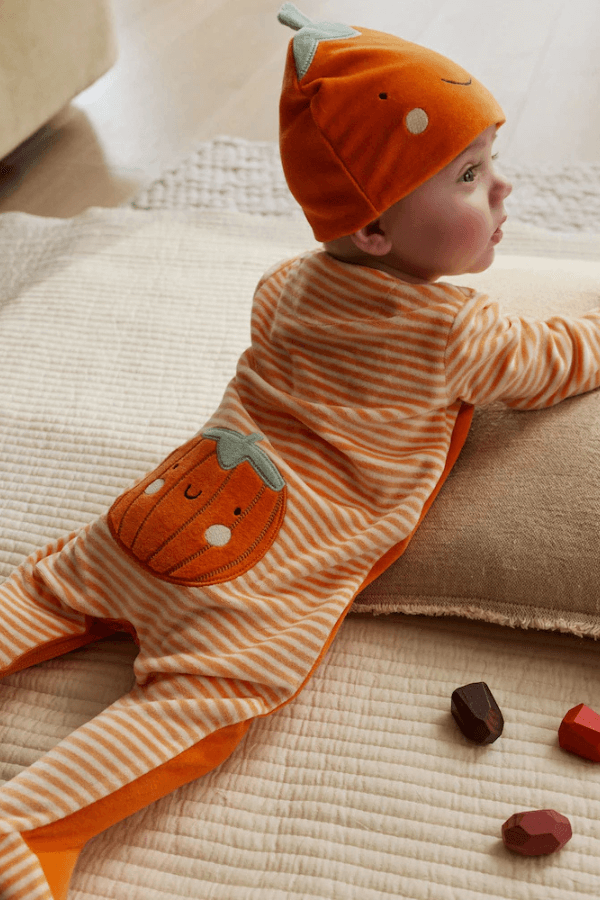 Małe dziecko w stroju z motywem dyni. Next.