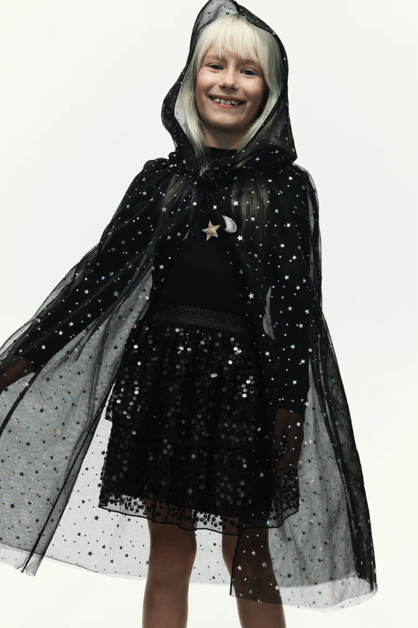Dziewczynka w czarnym stroju w gwiazdki. Kostiumy dla dzieci na Halloween.